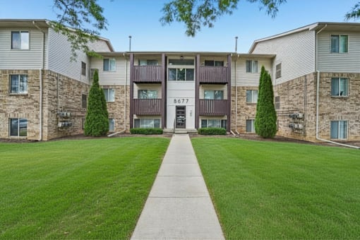 The image shows a well-maintained lawn in front of a building with the number 8677 on it.