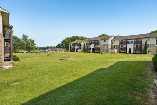 A grassy field in front of apartment buildings.
