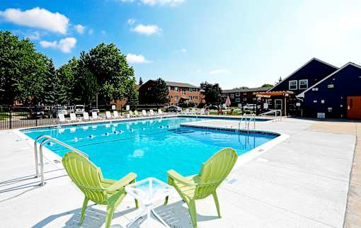 Two green chairs are placed on the edge of a blue swimming pool.