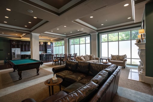 Club room at Residences of Creekside with brown leather couches and pool table.