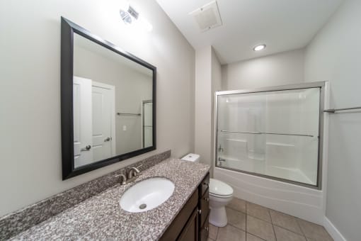 Bathroom with large mirror. Updated granite vanity with sink, toilet, and shower tub combo.