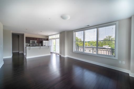 Kitchen, and living area with dark hardwood like floors and large picture windows at the Residences of  Creekside.