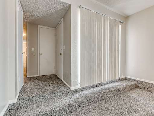 A room with a carpeted floor and a bed with white curtains.