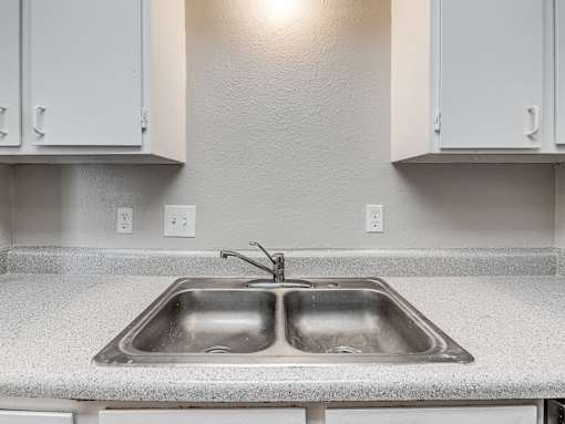 A kitchen with a double sink and white cabinets.