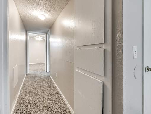 A long hallway with a light on the ceiling and a door on the right.