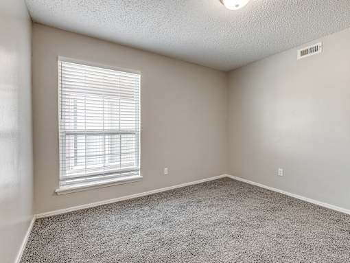 A room with a window and carpeted floor.