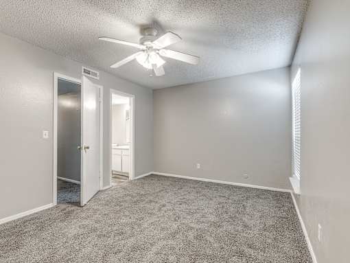 A room with a ceiling fan and carpeted floor.