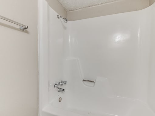 A white bathtub with a shower head and faucet.