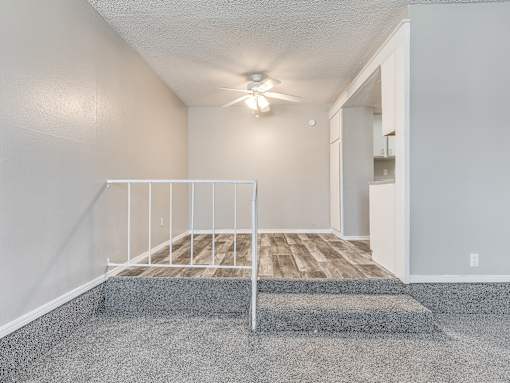 A bedroom with a bed, a ceiling fan, and a doorway leading to another room.