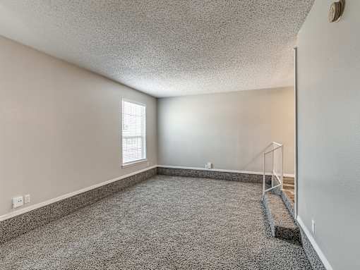 A room with a carpeted floor and a window with blinds.