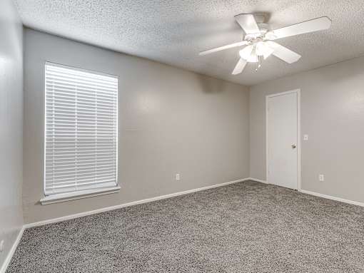 A room with a ceiling fan and a window with blinds.