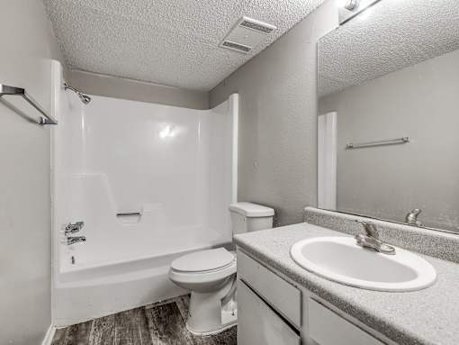 A white bathroom with a toilet, sink, and shower.