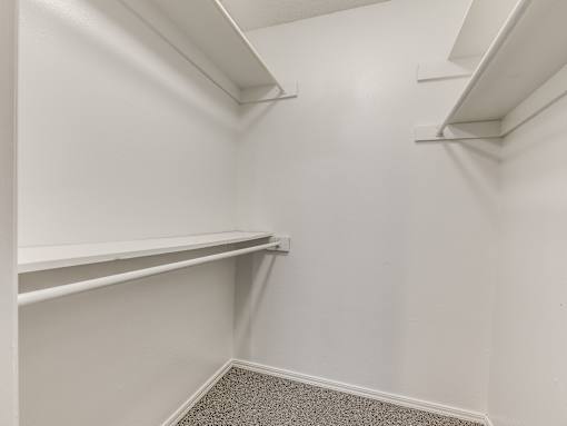A white closet with shelves and a carpeted floor.