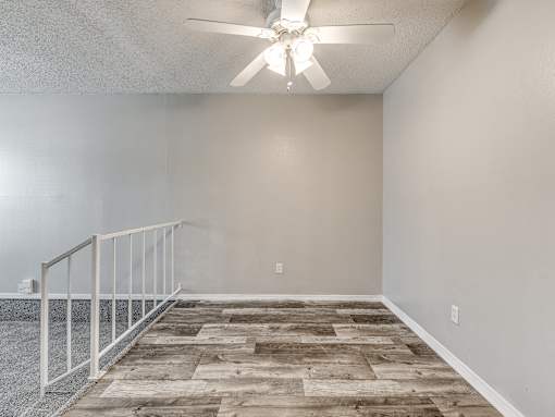 A room with a ceiling fan and wooden flooring.