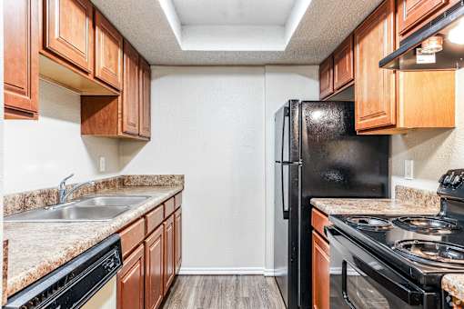 A kitchen with black appliances and wooden cabinets.