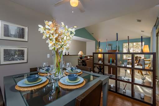 A dining room with a glass table set for two.