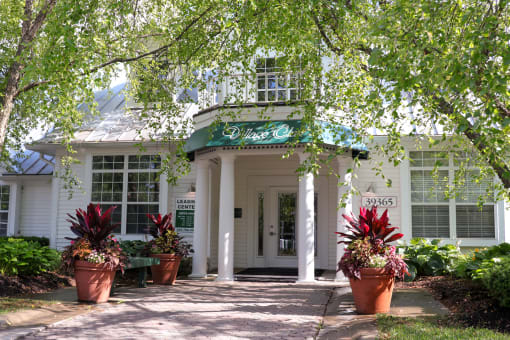 a white building with potted plants in front of it at Village Club of Farmington Hills, Farmington Hills, 48331