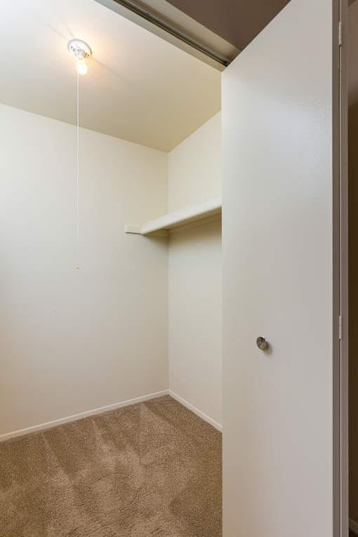 A small, empty room with a carpeted floor and a single light fixture on the ceiling.