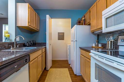 A kitchen with white appliances and wooden cabinets.