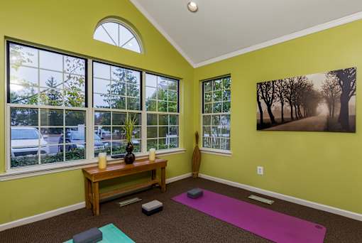 A room with a green wall and a purple yoga mat on the floor.
