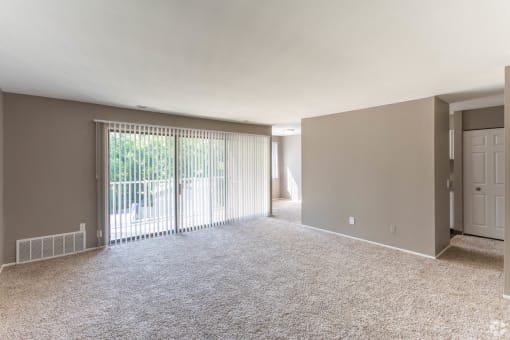 Living room with sliding glass door, gray walls, and plush carpeting