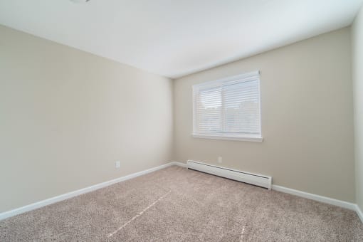 Bedroom with window, carpet, and baseboard heater