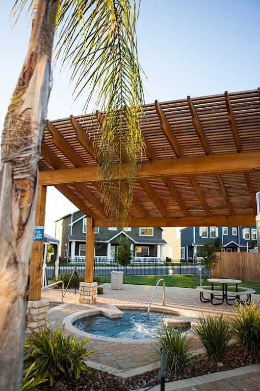 A wooden pergola over a hot tub in a backyard.