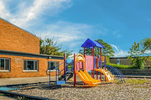 A playground with a yellow slide and a blue and pink structure.