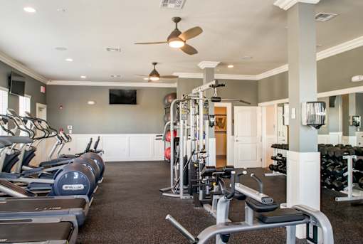A gym with treadmills, weights, and exercise equipment.