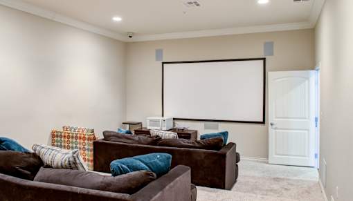 A living room with a couch, a chair, and a white screen on the wall.