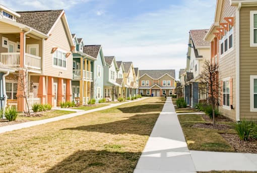 A row of houses with a sidewalk in front.
