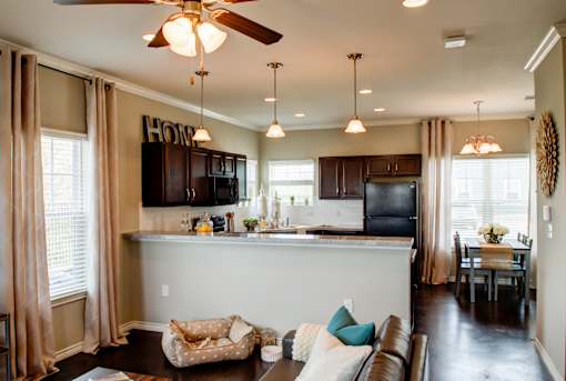 A kitchen with a brown couch and a ceiling fan.
