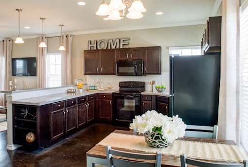 A kitchen with dark brown cabinets and a black refrigerator.