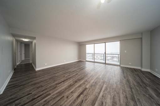an empty living room with wood flooring and a large window