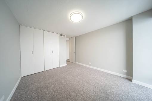 a bedroom with white walls and carpet and white cabinets