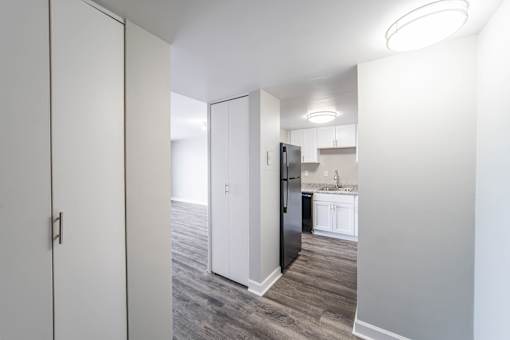 a renovated living room and kitchen with white cabinets and a black refrigerator