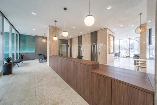 a large lobby with a wooden reception desk and glass walls