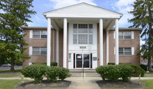 Exterior of Alexander Hamilton Plaza Apartments with green bushes in front