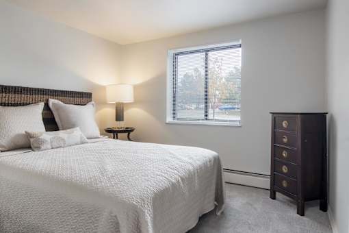 A bedroom with a large bed and a nightstand with a lamp.