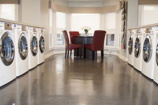 Communal laundry room with seating area and large windows.