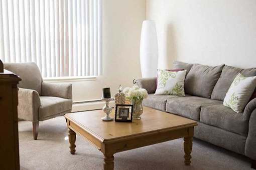 A living room with a grey couch, a wooden coffee table, and a grey armchair.