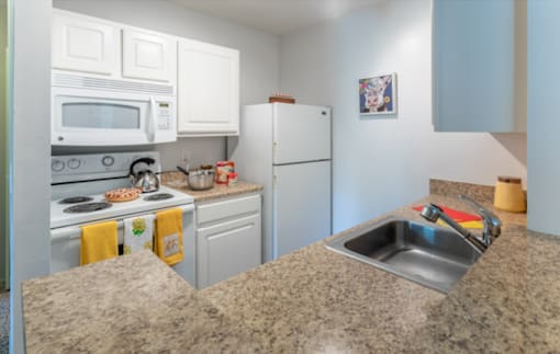 A kitchen with a refrigerator, oven, and microwave.