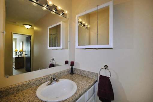 A bathroom with a sink, mirror, and lights.