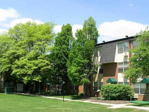 A green lawn in front of a building with trees.