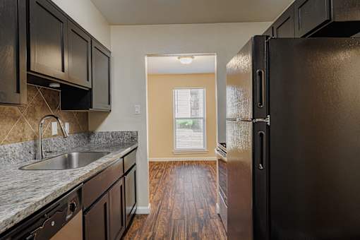 A kitchen with black cabinets and a black refrigerator.