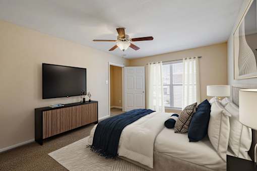 A bedroom with a bed, a television, and a ceiling fan.