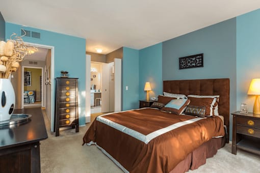 A bedroom with a brown bed and a chandelier.
