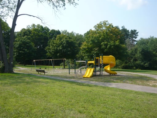 Playscape area in a park with trail and trees