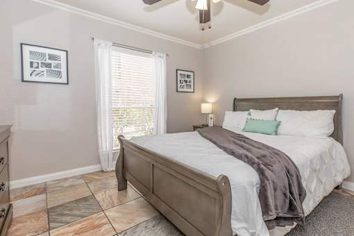 A bedroom with a bed, dresser, and ceiling fan.