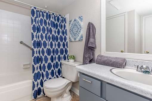 A white toilet with a blue shower curtain in a bathroom.